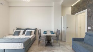 Ein modernes Schlafzimmer mit einem großen Bett, einem Esstisch mit Stühlen und einem blauen Sofa.