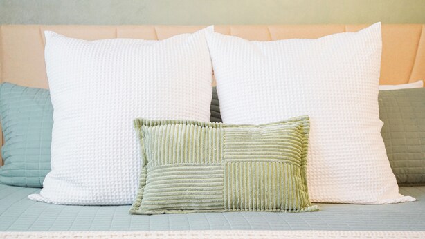 A bed with a quilted headboard and three pillows in different textures and colors. - The EBB TIDE-private pool + just mins to beach! (Palm Coast)