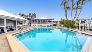 A pool area with lounge chairs, a covered seating area, and palm trees. - Manatee Harbor: Marina, Heated Pool-Spa, Island Ferry with PRIVATE Beach access! (Placida)