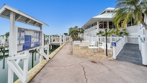 A marina with docked boats, a covered walkway, and a building with a ramp for accessibility. - Manatee Harbor: Marina, Heated Pool-Spa, Island Ferry with PRIVATE Beach access! (Placida)