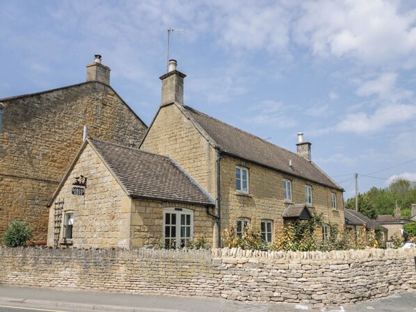 A stone building with a sign reading 'Robins Nest,' featuring a stone wall, multiple chimneys, and a tiled roof.