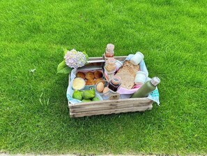 Una cesta de picnic sobre césped con alimentos como pan, huevos y pasteles.