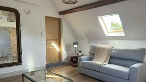 A modern living room with a glass coffee table, a light blue sofa, and a wooden door. - Bienvenue à la Ferme (Maresches)