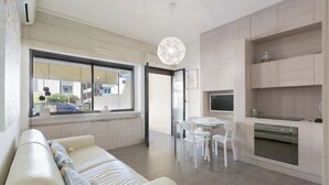 Una cocina moderna con horno integrado, un comedor con mesa y sillas, y un amplio ventanal que ofrece vistas al exterior.