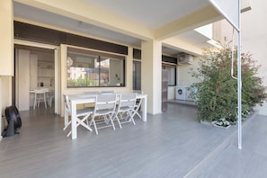 Une cuisine moderne avec des meubles blancs, un coin repas comprenant une table et des chaises, et une petite plante en pot.