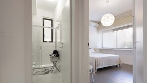 Un baño moderno con cabina de ducha de vidrio, una pequeña zona de estar y un inodoro a la vista.
