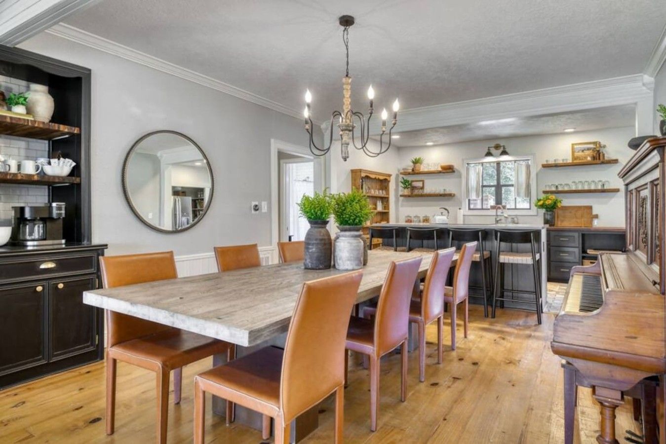A dining area with a large wooden table, multiple chairs, and a chandelier.