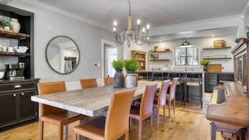 A dining area with a large wooden table, multiple chairs, and a chandelier.