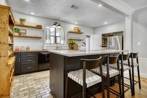 A modern kitchen with a central island, bar stools, and built-in appliances. - The Farmhouse at Fable Farm, 15 mins to Round Top! (Washington County)