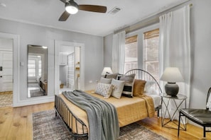 A bedroom with a bed, bedside tables, a ceiling fan, and a view of the outside through a window. - The Farmhouse at Fable Farm, 15 mins to Round Top! (Washington County)