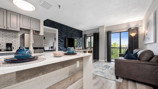 A modern kitchen with a central island, grey cabinets, and a black accent wall. - Apartment next to International Dr and Universal (Orlando)