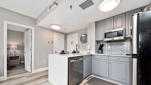 A modern kitchen with grey cabinets, stainless steel appliances, and a white island. - Apartment next to International Dr and Universal (Orlando)