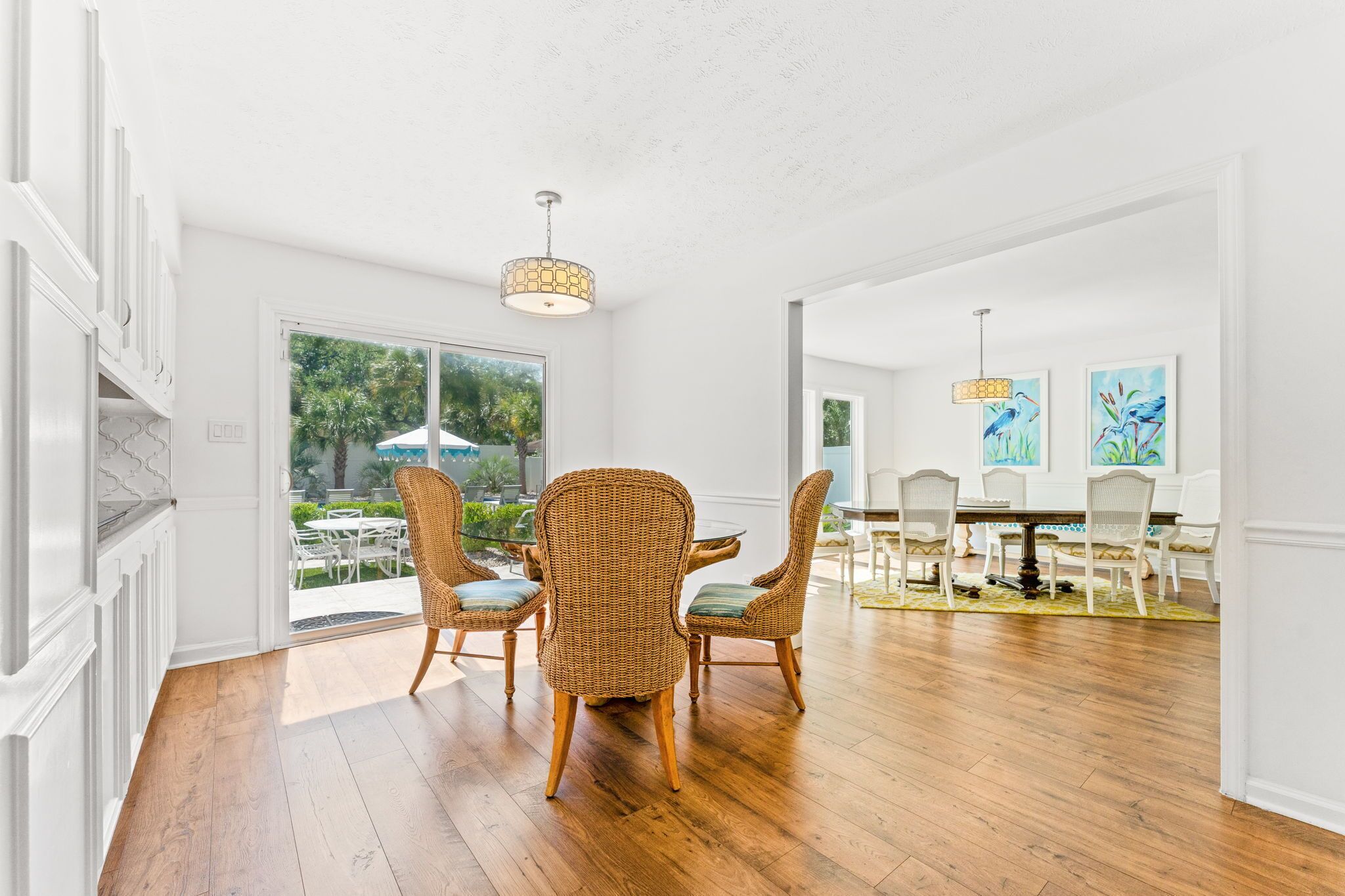 A dining area with wicker chairs, a wooden table, and a view of the outdoors.