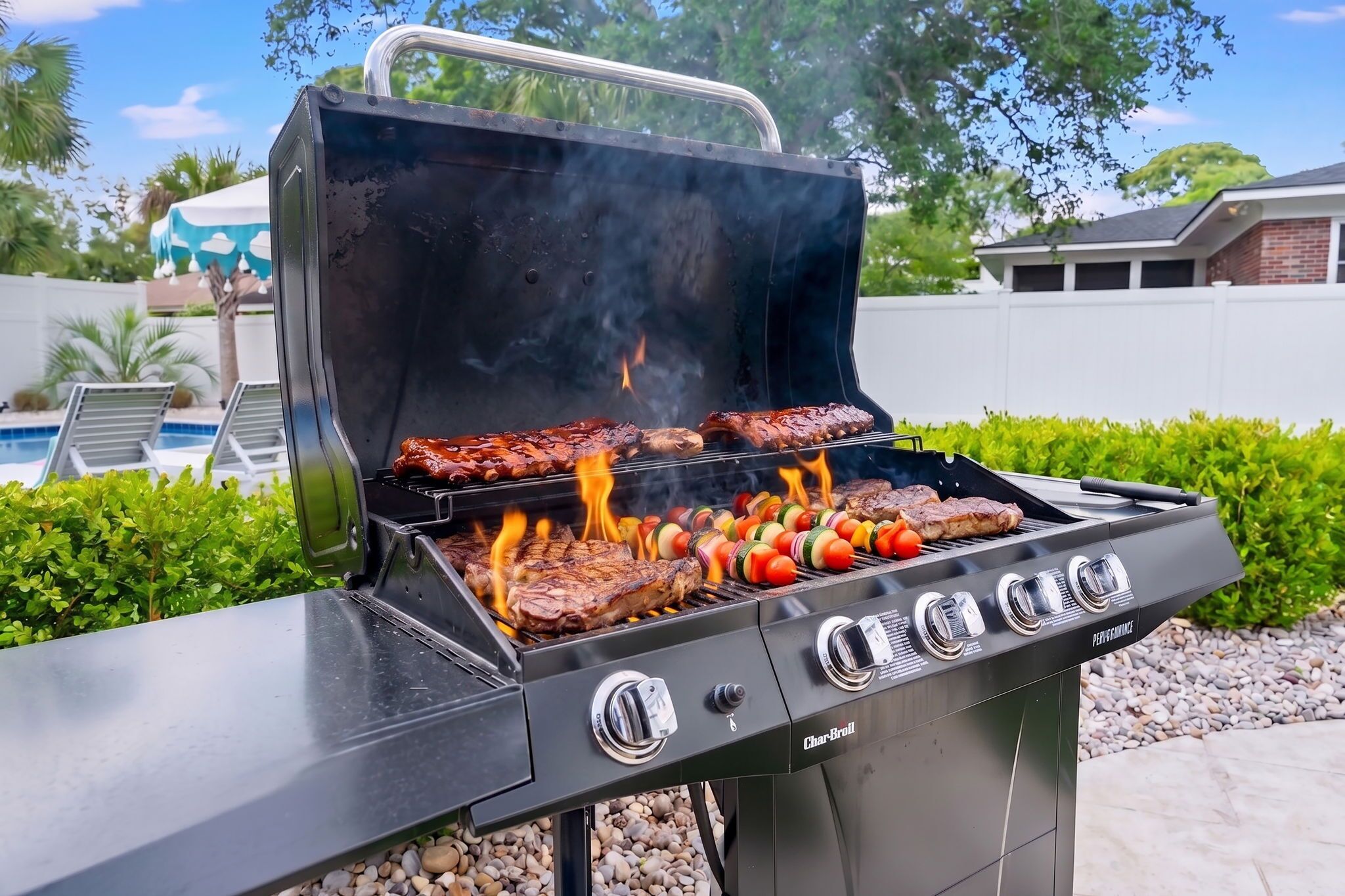 A Char-Broil grill with multiple cooking zones, a pool, and a white fence in the background.