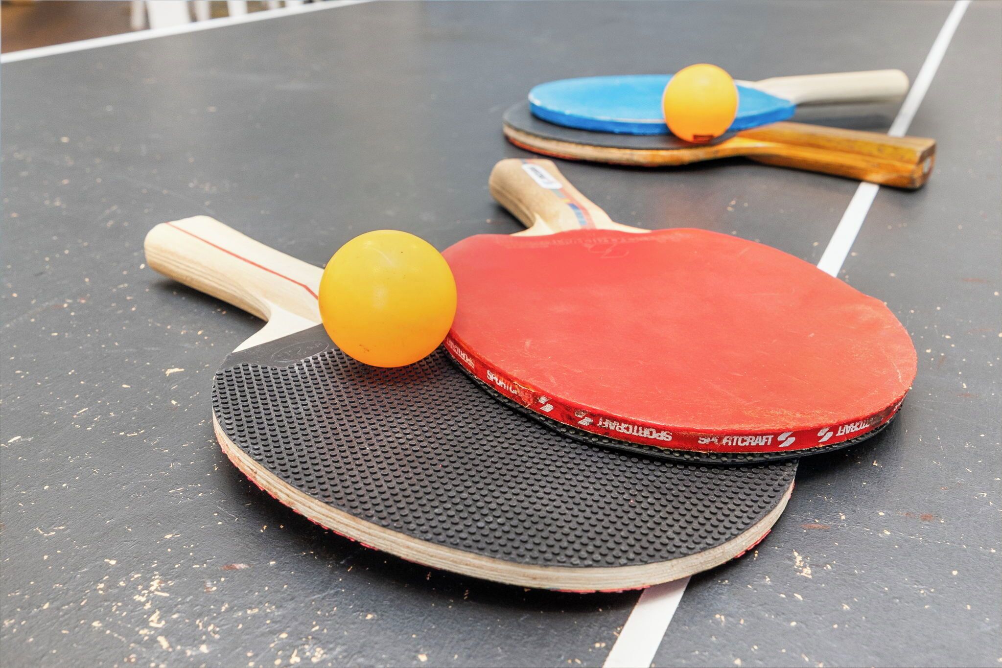 Pöytätennispöytä, jossa on kaksi mailaa ja kaksi palloa.