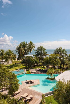 A resort pool with palm trees and a beach view. - Auka Boipeba (Cairu)