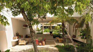 A modern outdoor patio with seating, plants, and a staircase leading to an upper level. - Auka Boipeba (Cairu)