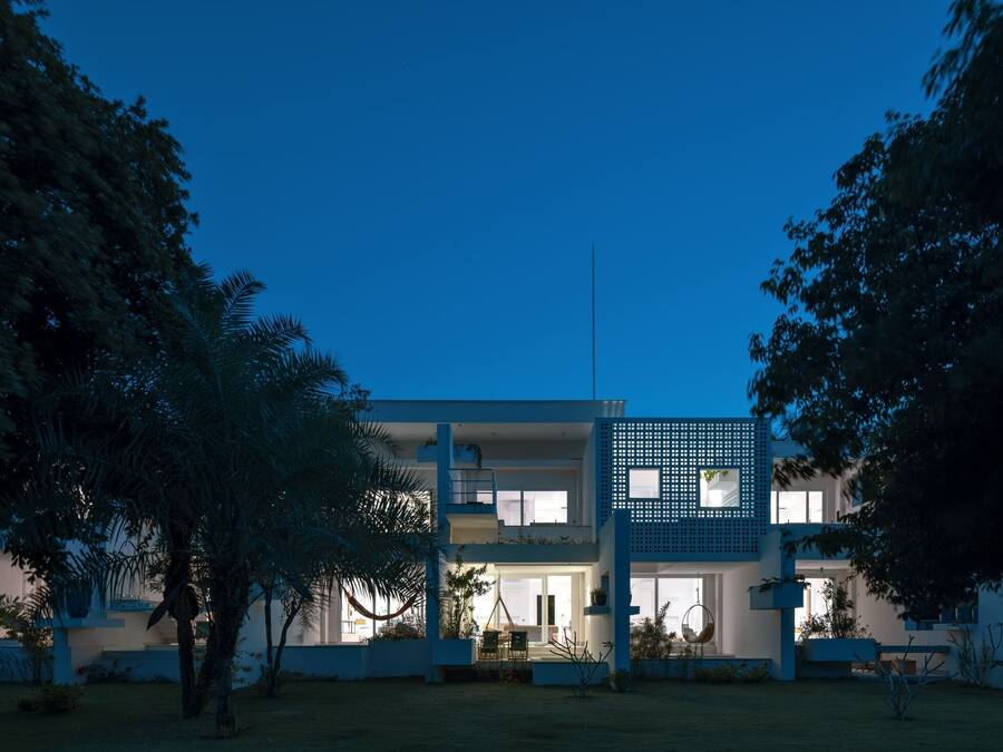 A modern two-story house with a flat roof, large windows, and a balcony.