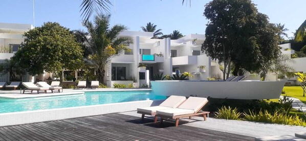 A modern hotel with a swimming pool, lounge chairs, and tropical landscaping. - Auka Boipeba (Cairu)
