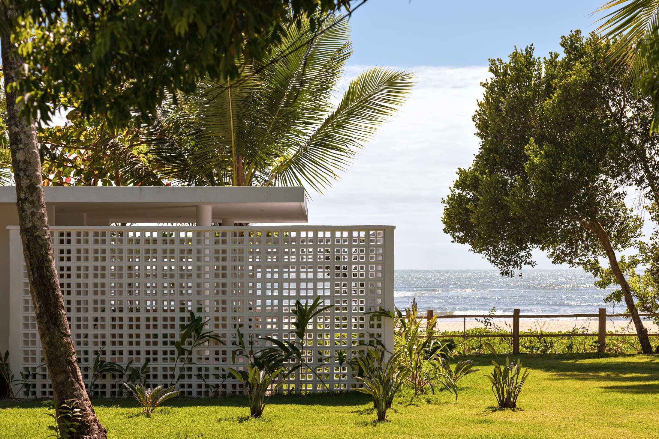 A white lattice fence with a view of the ocean.