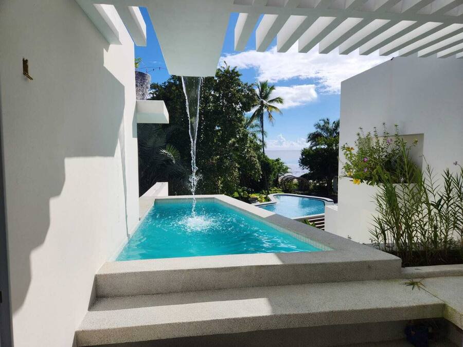 Ein Pool mit Wasserfall, umgeben von Stufen und Grünpflanzen.