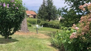 Eine grüne Fläche mit einem Baum, einem weißen Stuhl und einem Gebäude im Hintergrund.