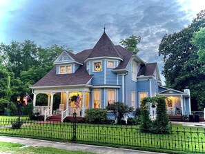 A large, two-story house with a wrap-around porch, a gabled roof, and a small tower-like structure on the roof. - Benefield House Bed & Breakfast (Jefferson)