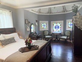 Un dormitorio con cama, mesita de noche y una pequeña zona de estar con sillas y una mesa.