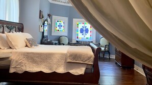 A bedroom with a large bed, a wooden dresser, and a desk with a chair.