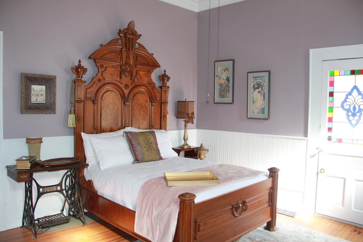A bedroom with a wooden bed, a sewing machine, and framed pictures on the wall.