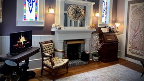 A cozy living room with a fireplace, a television, and a comfortable armchair.