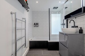 A modern bathroom with a bathtub, a sink, and a glass shower enclosure.