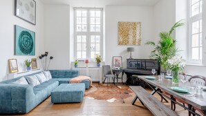 A living room with a blue sofa, a dining table set for four, and a cowhide rug. - Luxurious & Chic 2BD Warehouse Flat - Old Street! (London)