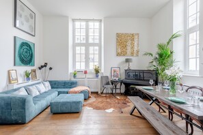 A living room with a blue sofa, a dining table set for four, and a cowhide rug.