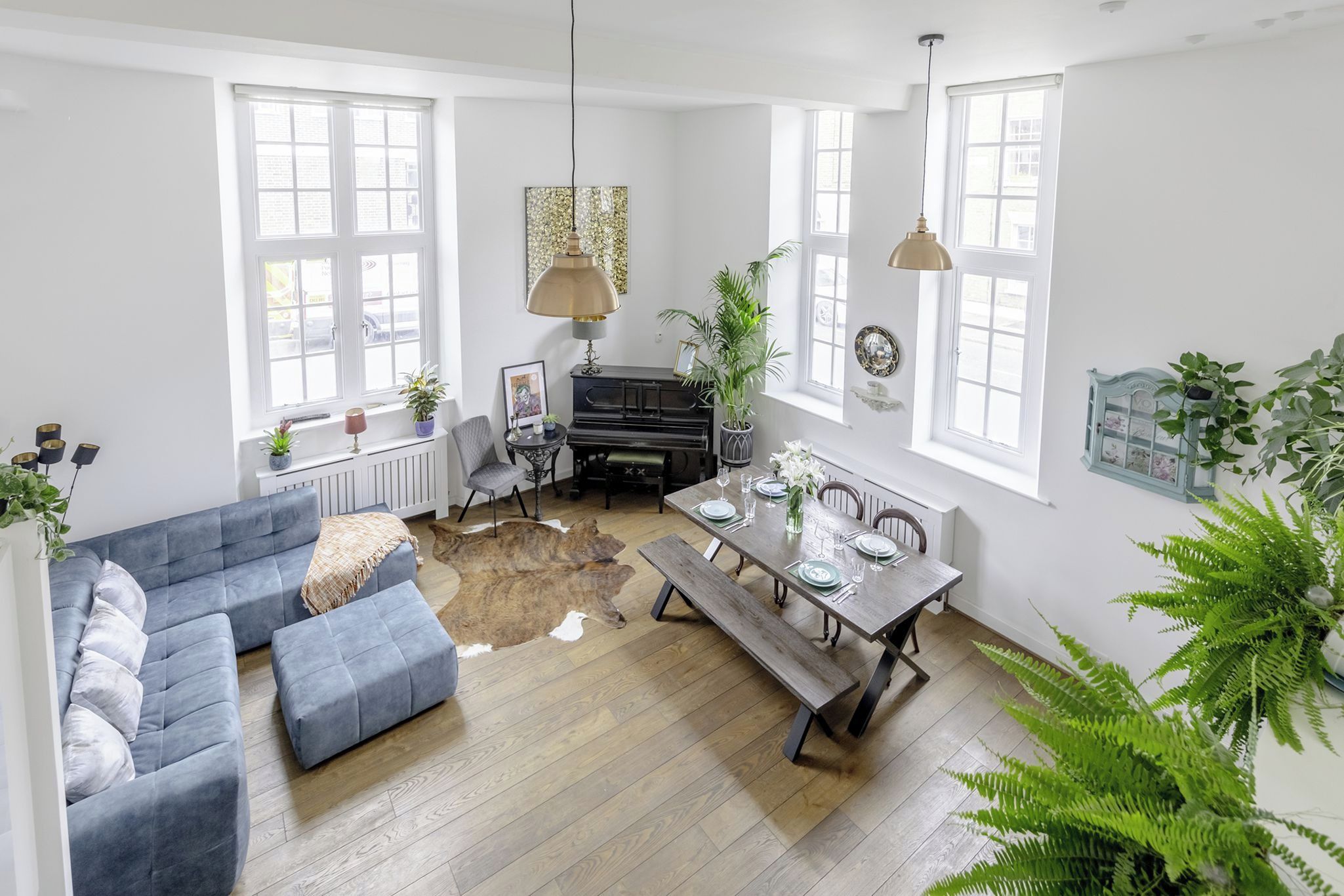 Een ruime woonkamer met een bank, een eettafel voor vier personen en een piano.
