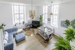 Un amplio salón con un sofá, una mesa de comedor para cuatro personas y un piano.