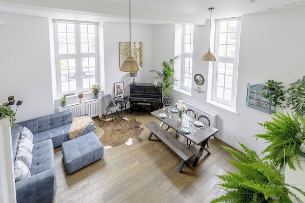A spacious living area with a sofa, a dining table set for four, and a piano.