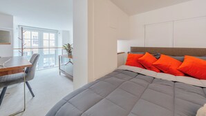 A modern bedroom with a large bed, a desk, and a chair. - Luxurious & Chic 2BD Warehouse Flat - Old Street! (London)