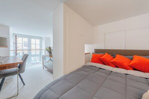 A modern bedroom with a large bed, a desk, and a chair.