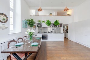 A modern kitchen with white cabinets, a built-in oven, and a coffee machine.