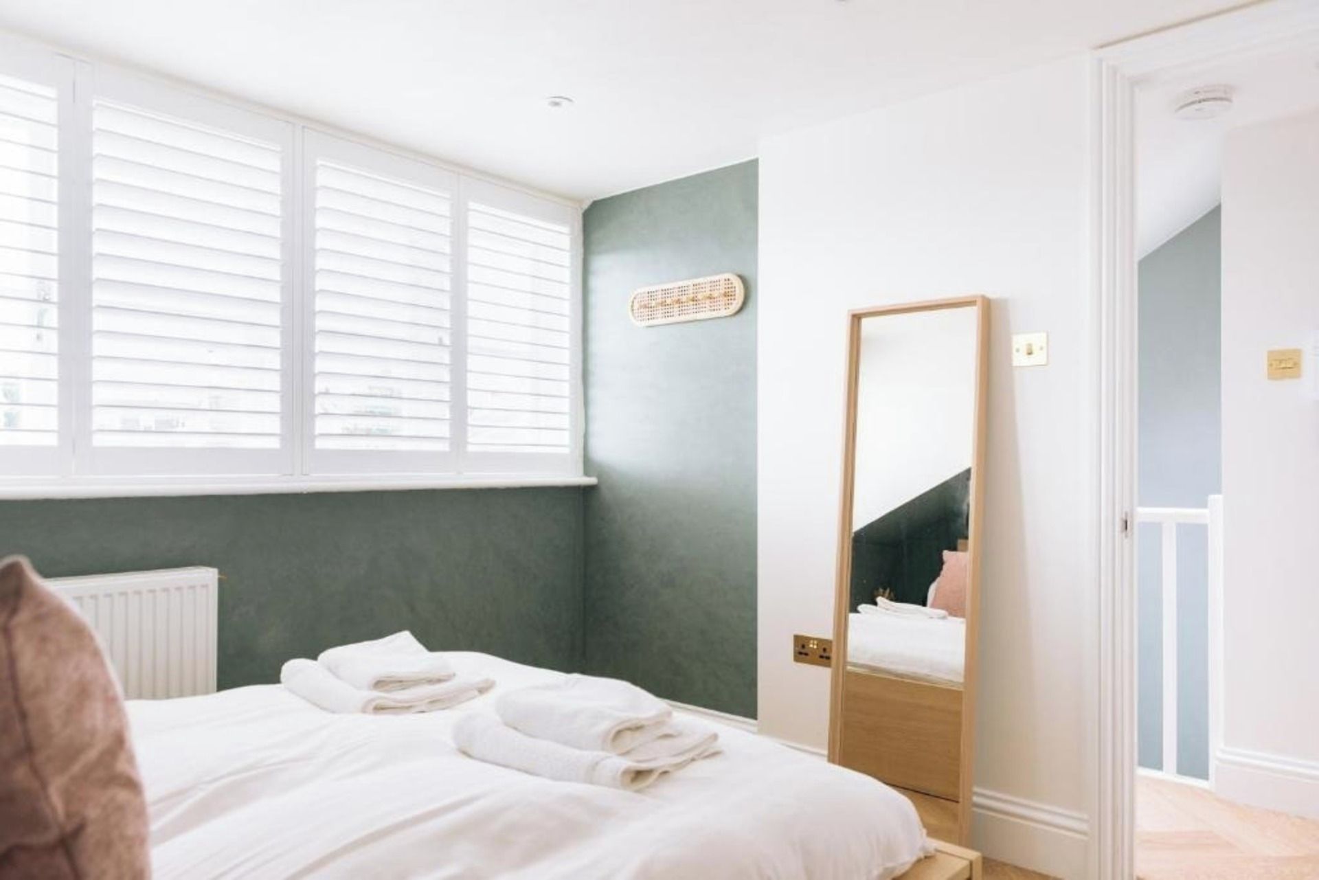A hotel room with a bed, a large mirror, and a window with blinds.