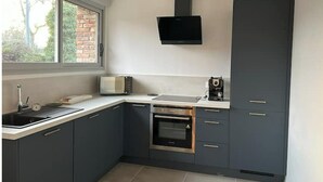 A modern kitchen with dark cabinetry, a built-in oven, a microwave, and a large window providing natural light.