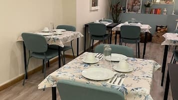 Un comedor con mesas dispuestas para cuatro, sillas y un equipo de aire acondicionado instalado en el techo.