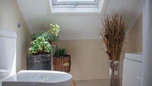 A bathroom with a skylight, a bathtub, and two potted plants. - O'Porto Seven - Guest House (Porto)