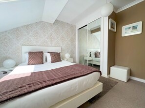 Relax in this serene bedroom with a large bed, a bedside table, and a comfortable chair.