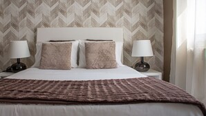 A neatly made bed with two pillows, a brown blanket, and two bedside lamps on a nightstand. - O'Porto Seven - Guest House (Porto)