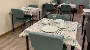 A dining area with tables set for four, each with floral tablecloths and green chairs. - O'Porto Seven - Guest House (Porto)
