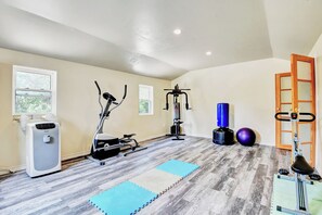 A home gym with exercise equipment, a standing bike, a rowing machine, a punching bag, and a yoga mat. - 17463 County Rd 18 (South Stormont)