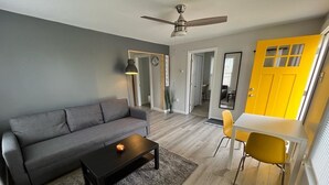 Una sala de estar moderna con un sofá gris, una mesa de centro negra y una silla amarilla.