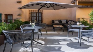 Eine Terrassesitzgruppe im Freien mit Korbmöbeln, einer Couch und einem großen Sonnenschirm.